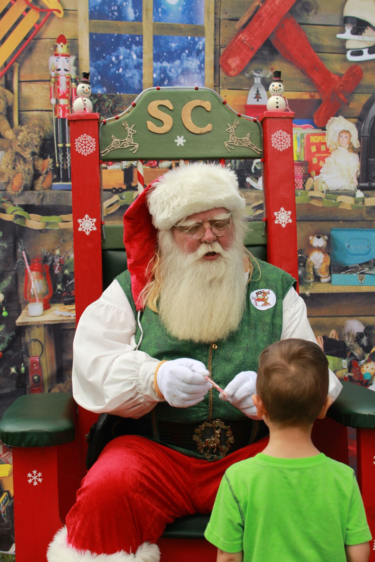 a little boy standing next to a santa clause